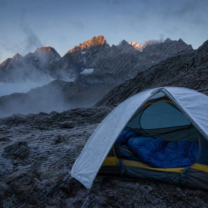 Sac de couchage momie dans une tente bivouac en montagne à l'aube