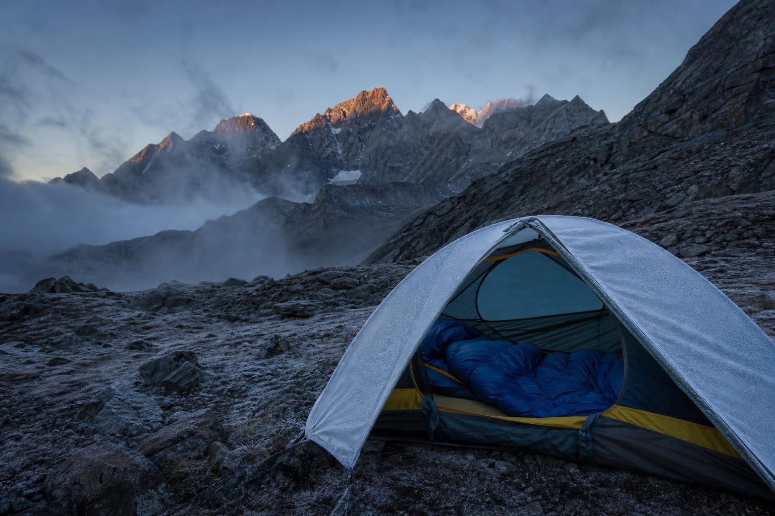 Sac de couchage momie dans une tente bivouac en montagne à l'aube