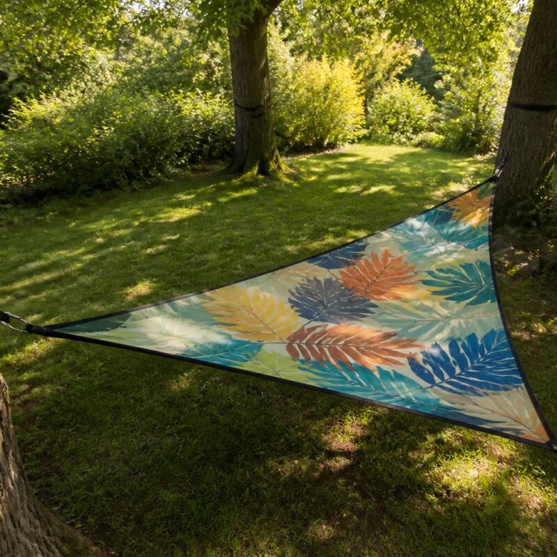Hamac triangle coloré suspendu entre trois arbres dans jardin verdoyant