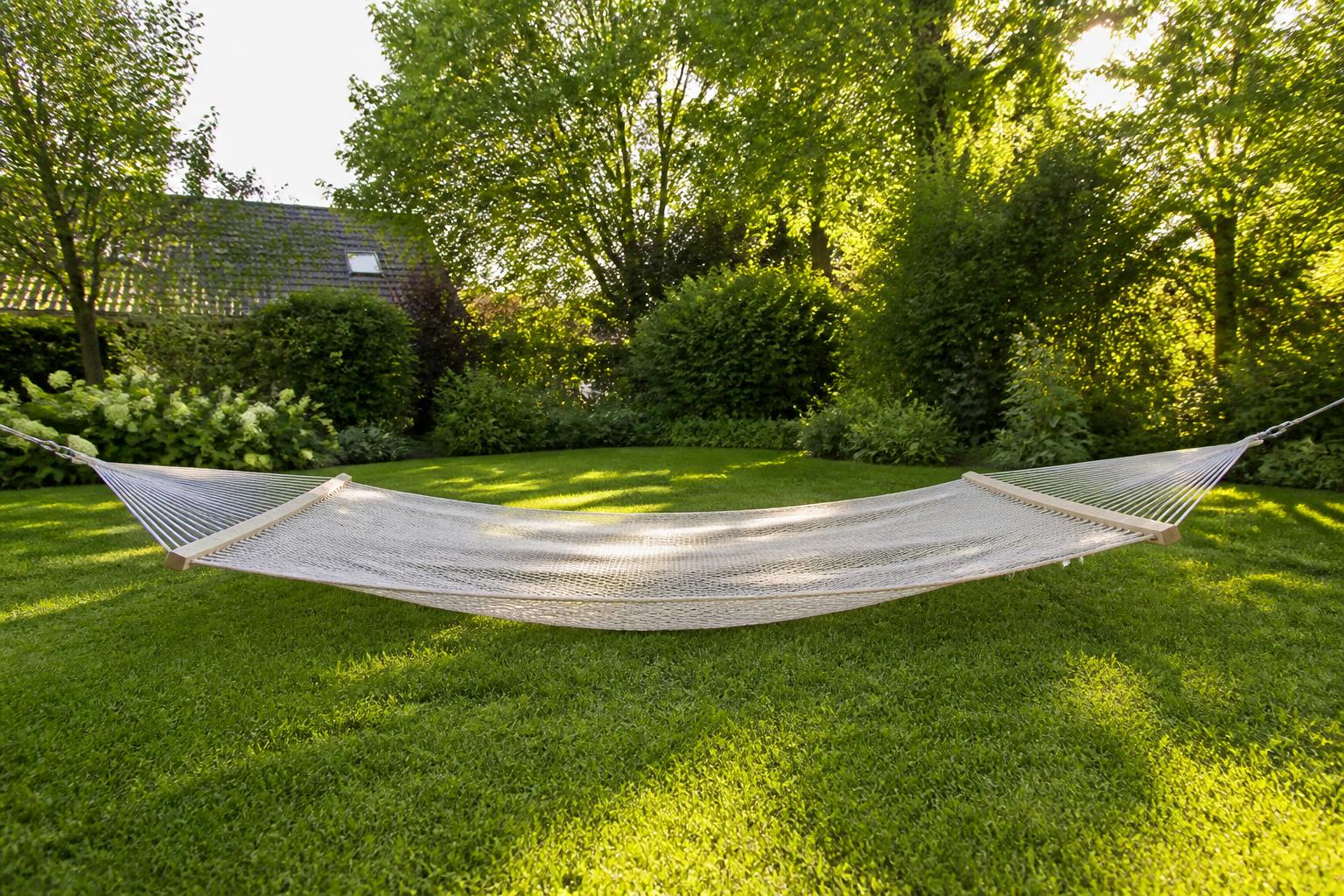 Hamac triangle en filet installé bas dans un jardin avec deux enfants