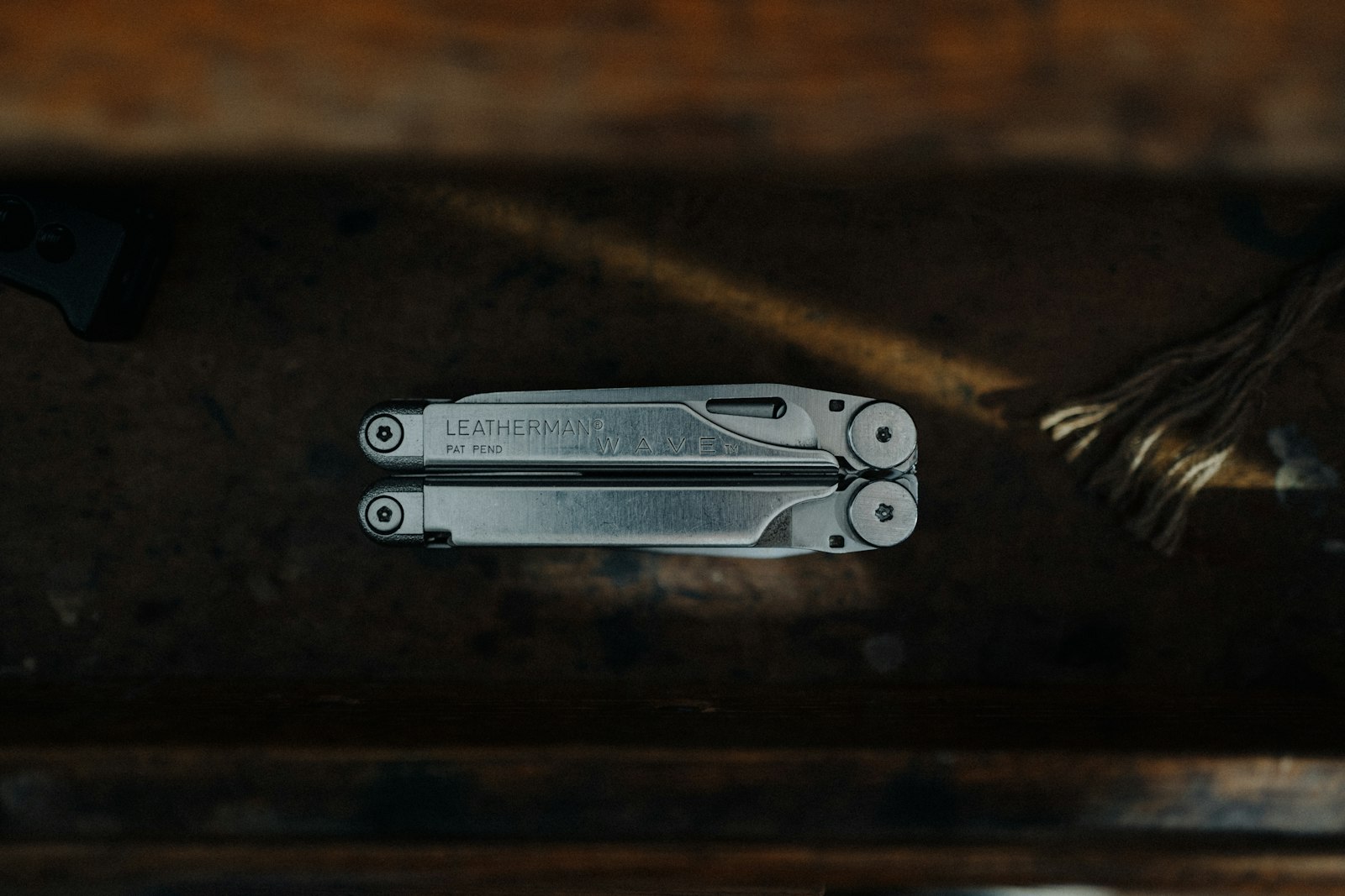 Pince multifonction Leatherman Wave en acier inoxydable posée sur un établi en bois