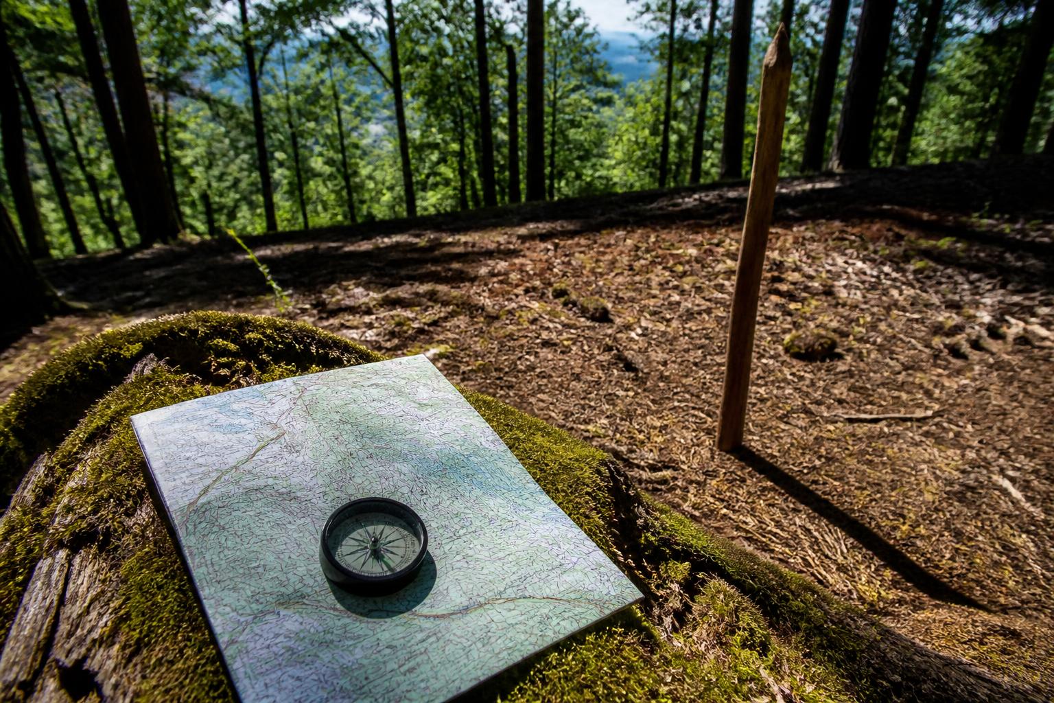 Boussole et carte papier sur tronc moussu pour orientation en forêt
